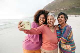 Three women taking a selfie on a beach with mountains in the background